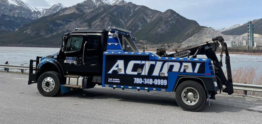 Action Towing heavy-duty wrecker truck parked on a mountain highway shoulder, providing professional semi truck towing and commercial vehicle recovery.